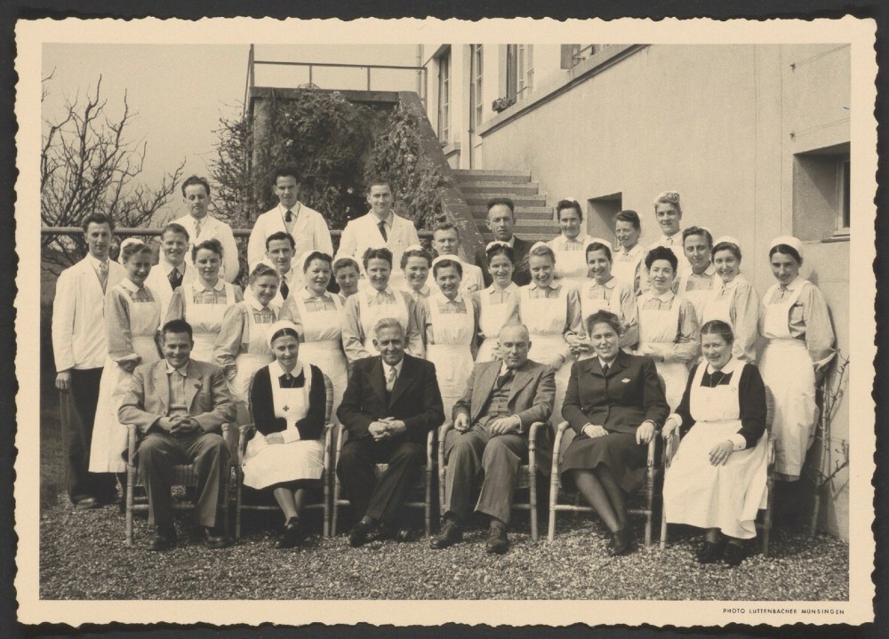 Fotografie zeigt den Psychiater Max Müller (im dunklen Anzug in der Mitte sitzend) mit der Belegschaft der Psychiatrischen Klinik Münsingen, 1951.