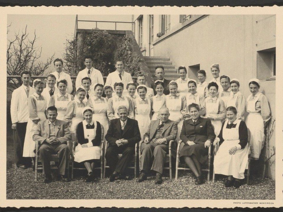 Fotografie zeigt den Psychiater Max Müller (im dunklen Anzug in der Mitte sitzend) mit der Belegschaft der Psychiatrischen Klinik Münsingen, 1951.