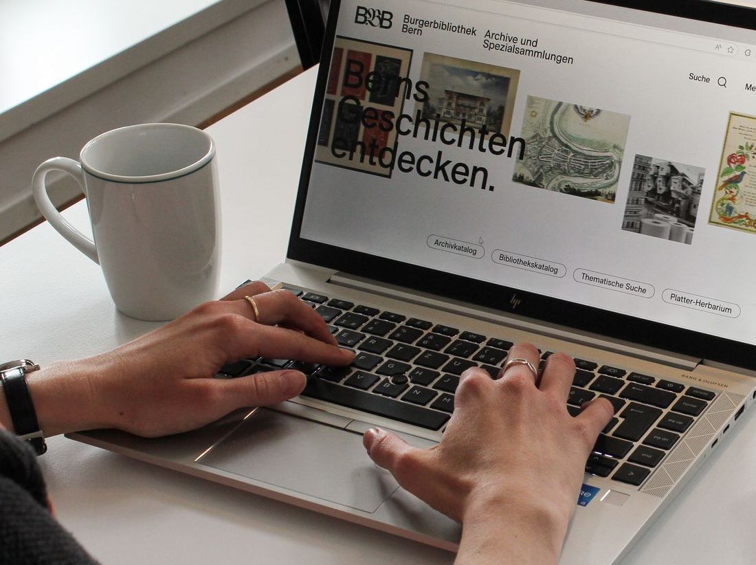 Eine Person, welche die Webseite der Burgerbibliothek Bern an einem Laptop besucht.