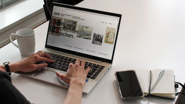 Eine Person, welche die Webseite der Burgerbibliothek Bern an einem Laptop besucht.