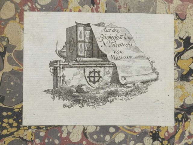 Zeichnung zeigt ein aufgerolltes Pergament auf welchem steht: «Aus der Büchersammlung N. Friedrichs von Mülinen». Im Hintergrund ist eine kistenartige Konstruktion, welche mit dem Familienwappen versehen ist und auf welcher mehrere Bücher stehen.
