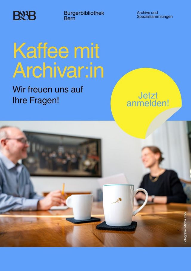 Zwei Kaffeetassen stehen auf einem Tisch. Im Hintergrund sind zwei Personen zu sehen, welche sich angeregt unterhalten.