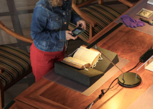 Eine Person im Lesesaal, welche mit ihrem Smartphone ein Buch abfotografiert.